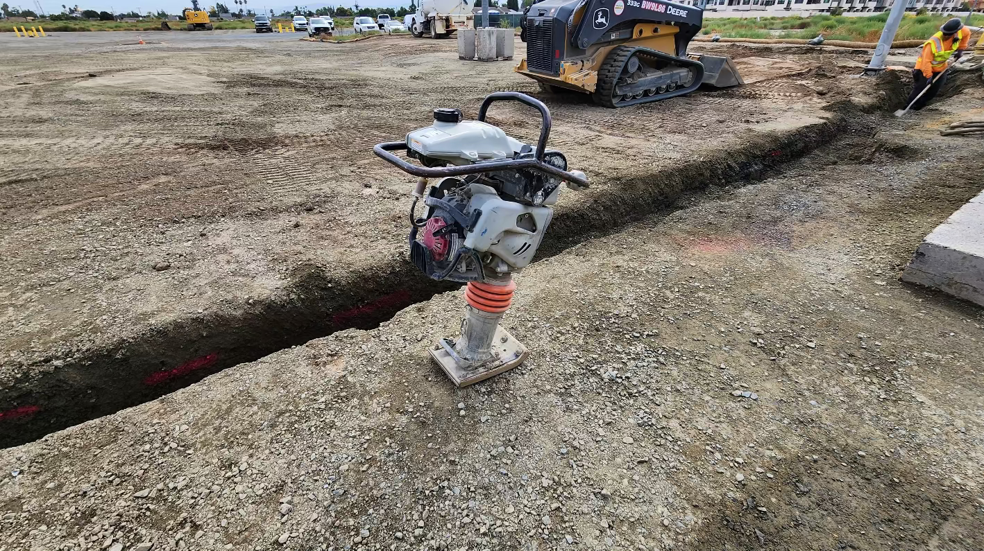 Gasoline-powered soil compactor, also known as a jumping jack, with upright handle and footplate designed for compacting soil in construction areas.”