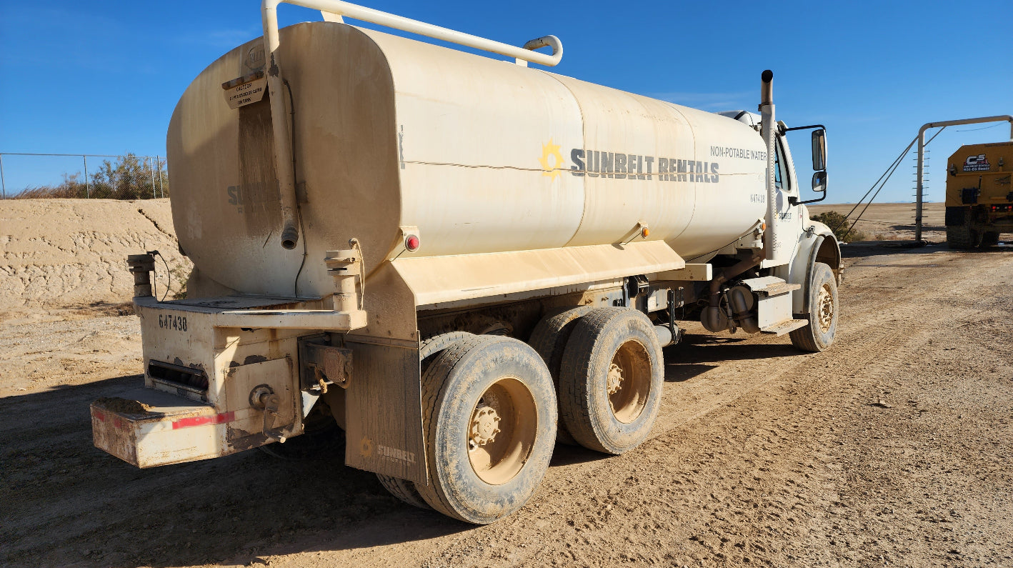 Water truck on a dirt road with clear blue sky awaiting water refill