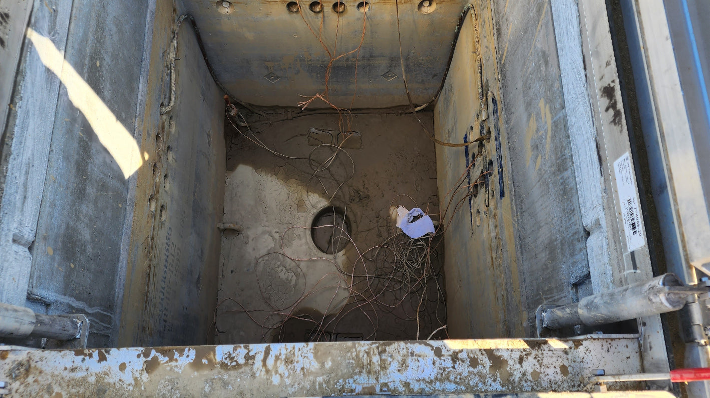 Newly installed open utility vault showing conduit penetrations and interior structure.