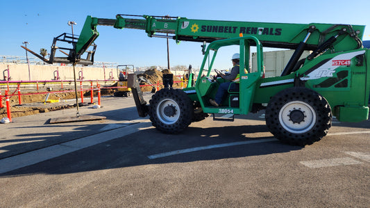 Green Reach-lift moving a trench plate a construction site.