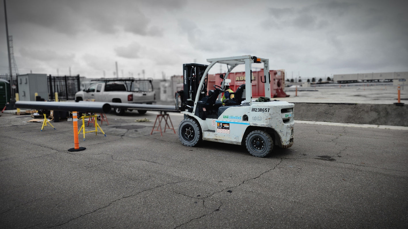 Forklift with a load on a concrete surface under an overcast sky