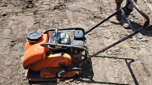 Portable Gas-powered vibratory plate on soil at property being landscaped and prepared for new sod installation