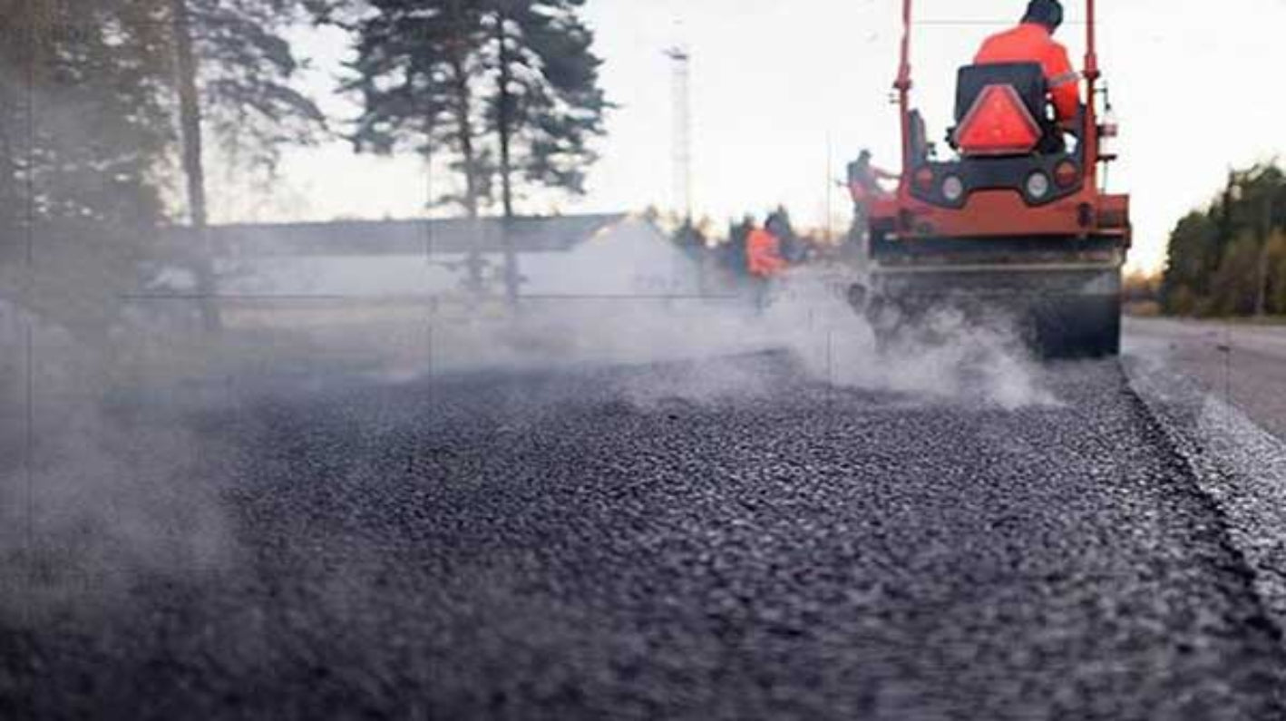 Heavy equipment roller compacting asphalt surface for road construction project.