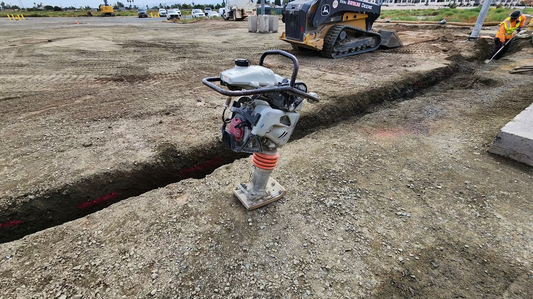 Gasoline-powered soil compactor, also known as a jumping jack, with upright handle and footplate designed for compacting soil in construction areas.”