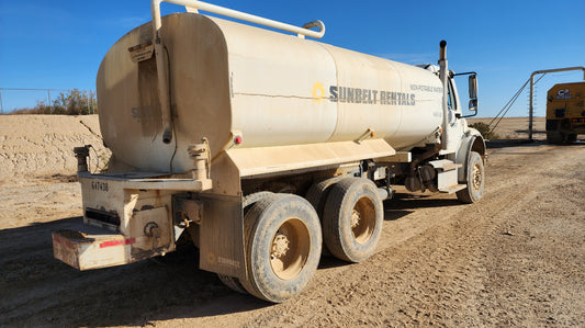 Water truck on a dirt road with clear blue sky awaiting water refill