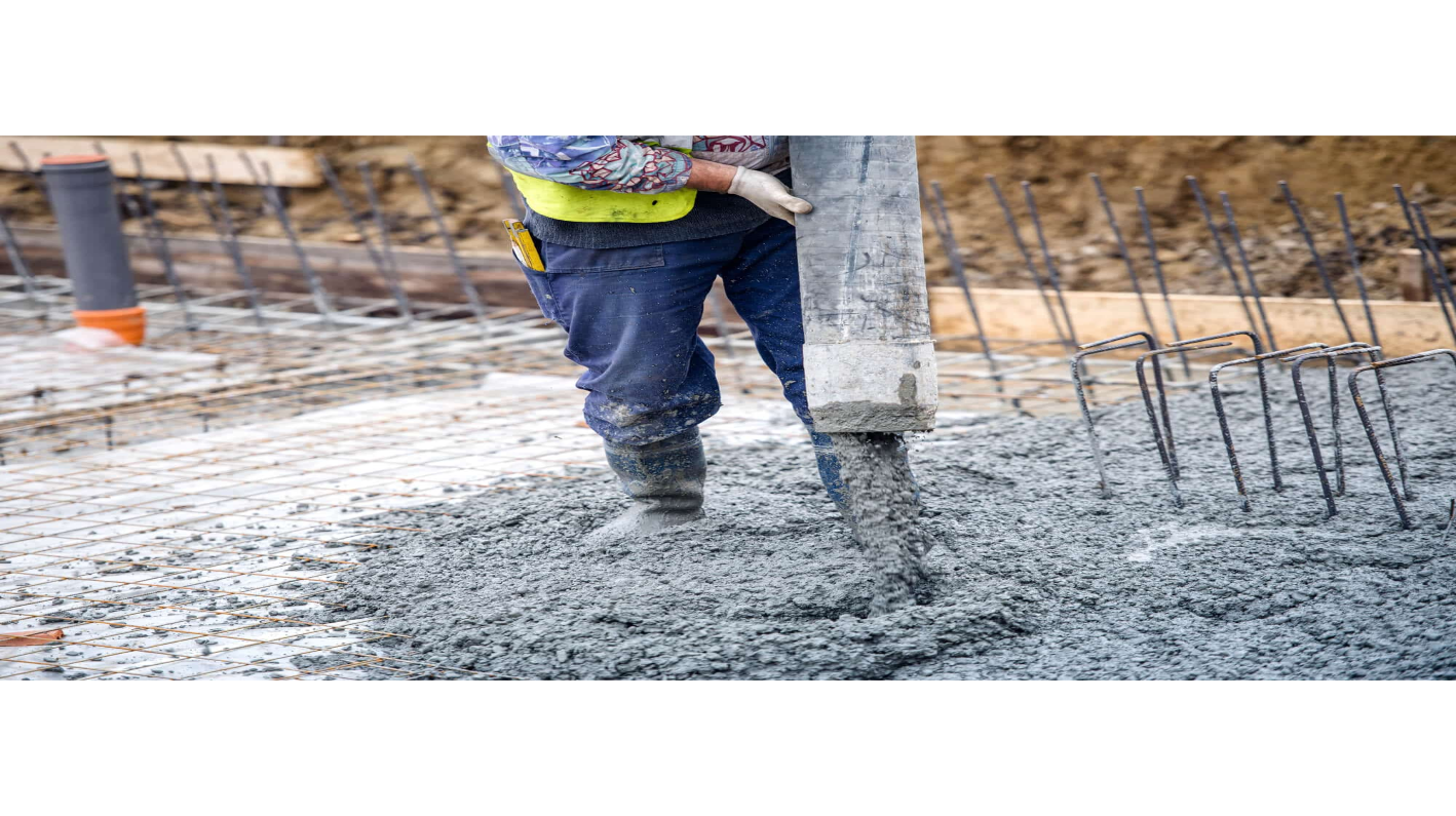 Person pouring concrete into a new form for a foundation on a construction site.